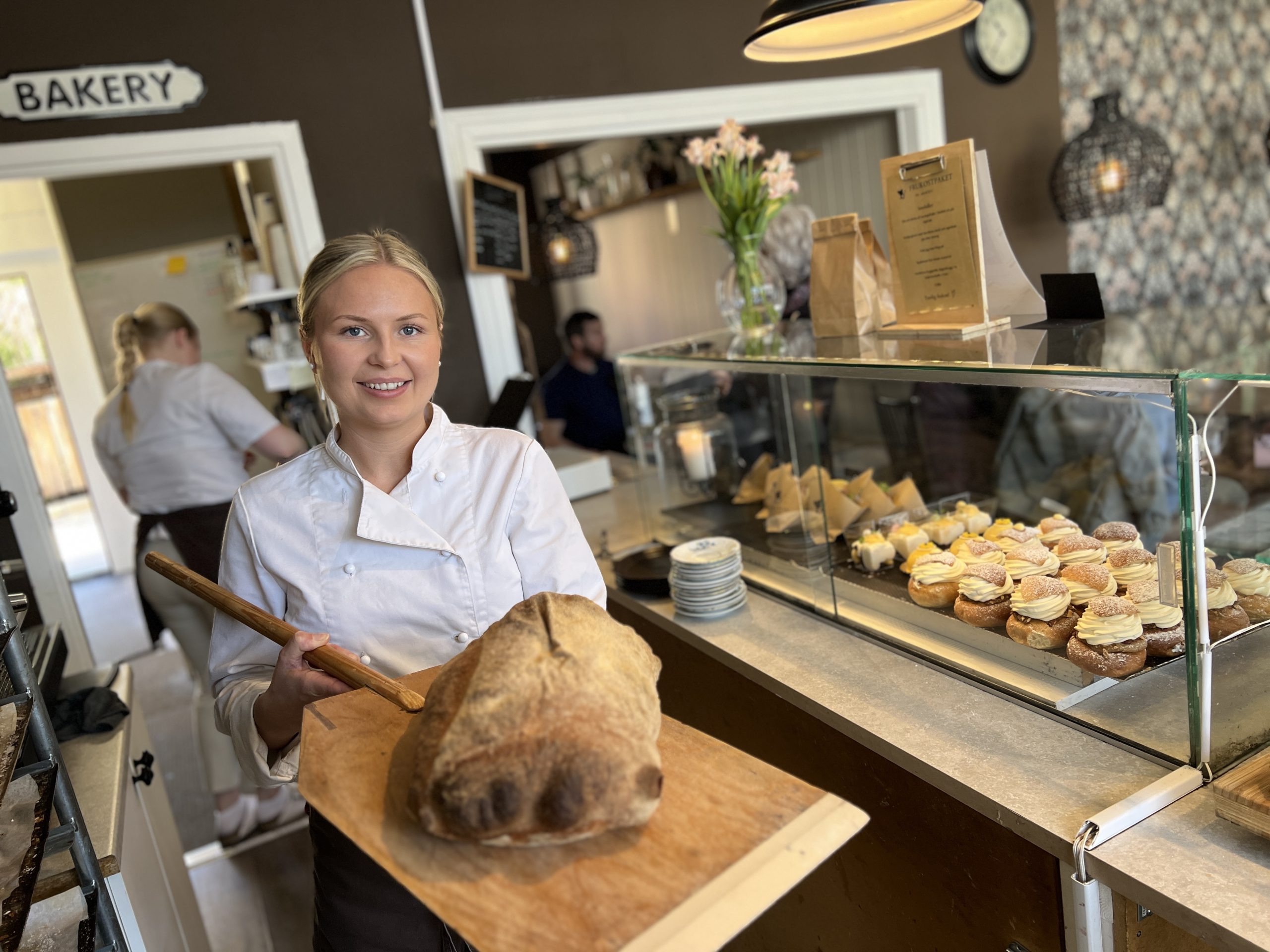 Kvinna håller upp brödspade med ett bröd på.